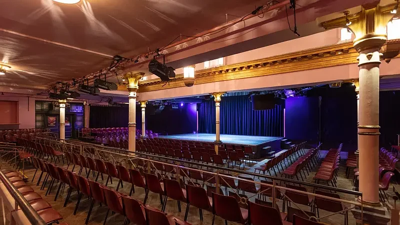 Beleuchteter Festsaal mit Theaterbühne und Bestuhlung