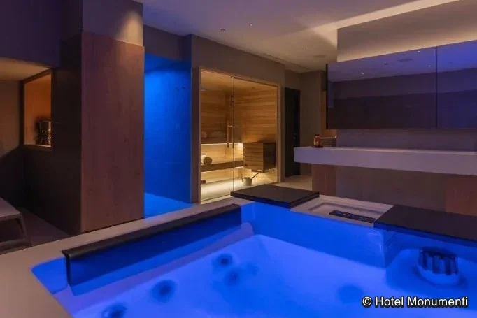 Moderner Wellnessbereich im Hotel Monumenti mit blau beleuchtetem Whirlpool und Saunabereich