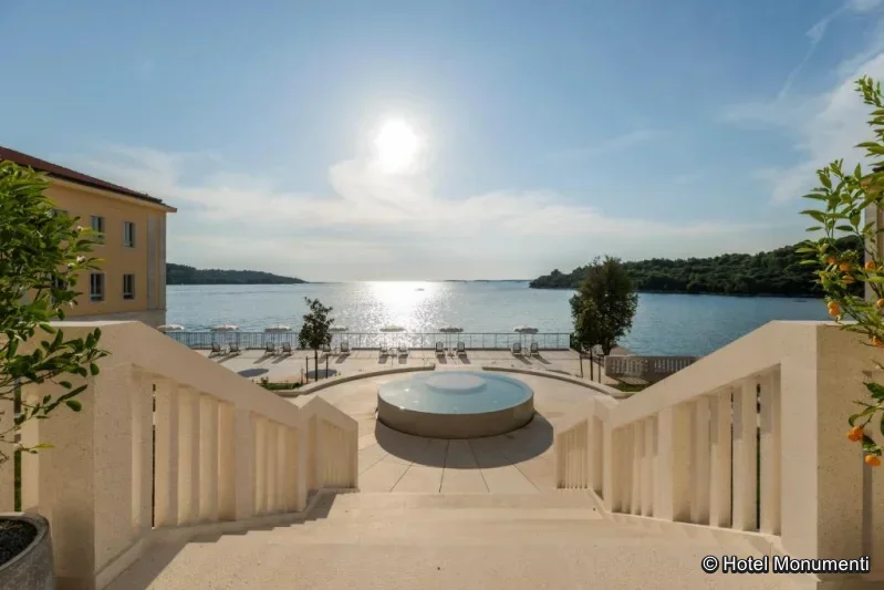 Hotelanlage direkt am Meer mit Sonnenterrasse, rundem Springbrunnen und Blick auf die ruhige Adriabucht.
