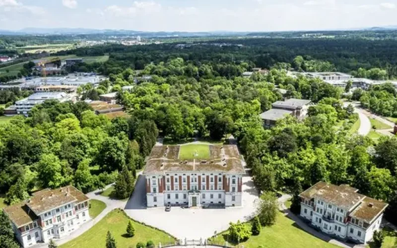 Drei Jugendstilgebäude inmitten von einer Parkanlage, Bäume und andere Gebäude im Hintergrund