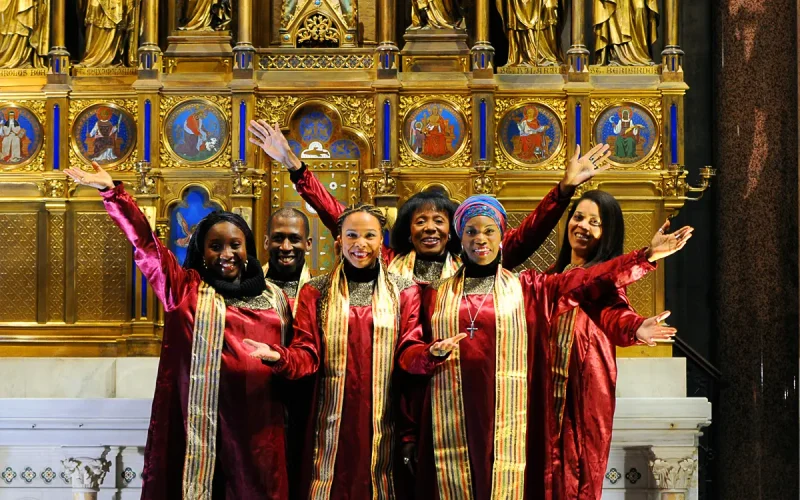 Sängerensemble in typischer roter Gospel-Singer-Bekleidung mit goldenen Schals vor einem Goldenen Altar